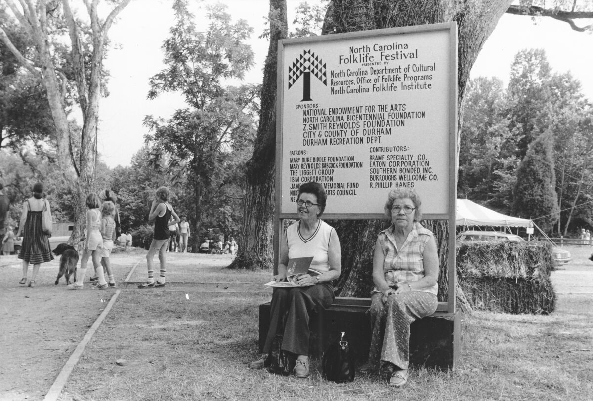 Patrons Resting by the Festival Sign